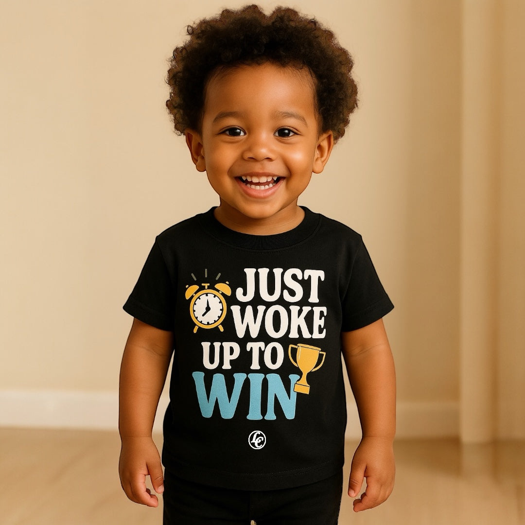 Child wearing a black t-shirt with motivational text and graphics, standing against a beige wall.
