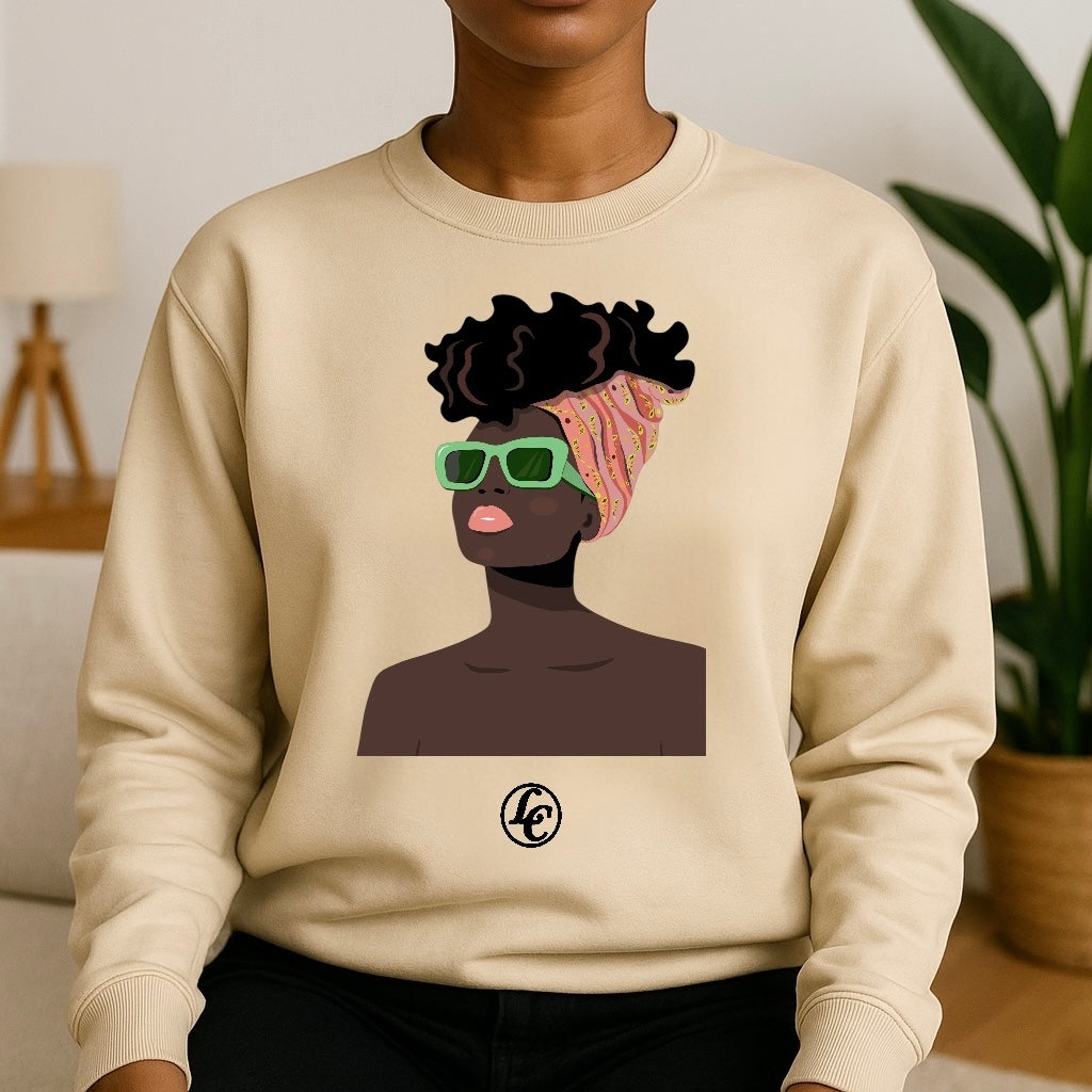 Beige sweatshirt with an illustration of a person with sunglasses and a headwrap, worn by a person indoors.