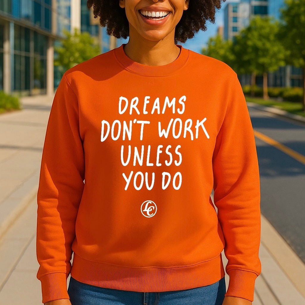 Person wearing an orange sweatshirt with motivational text outdoors.