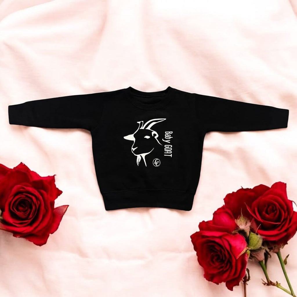 Black sweatshirt with a white goat graphic and text on a rose sheet background