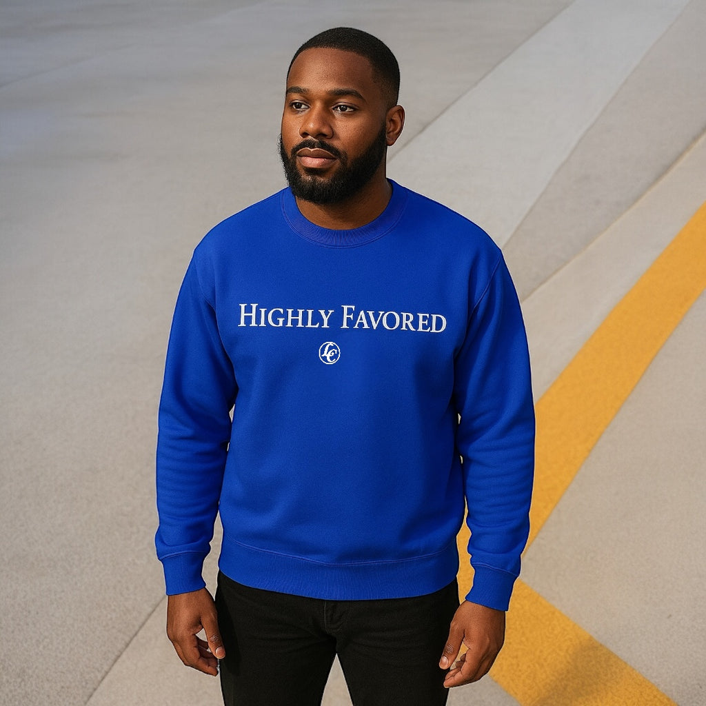 Man wearing a blue 'HIGHLY FAVORED' sweatshirt against a geometric background